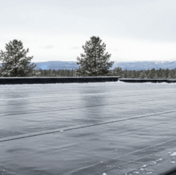 EPDM roof with snow and two cans of Butyl Liquid Rubber for winter protection and sealing.