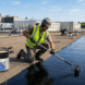 Contractor applying liquid EPDM rubber roof coating on a flat commercial roof for seamless waterproof protection.