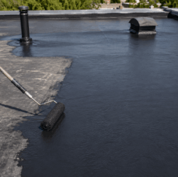 Worker applying liquid rubber coating to repair a leaking EPDM rubber roof without full roof replacement