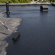 Worker applying liquid rubber coating to repair a leaking EPDM rubber roof without full roof replacement