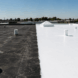 Professional roofer applying reflective EPDM roof coating for UV protection and energy savings