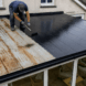 Professional applying waterproof roof coating to repair an old metal sunroom roof
